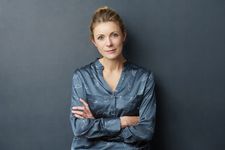 Woman with her arms crossed while leaning against wall